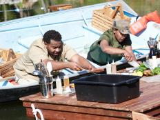 Chefs Demarco Ellis and Candice Wilson preparing their dishes, Tropical Trout and Head to Tail Trout Dinner, on the Round 1 sabotage element, Boat Prep & Cook, as seen on Food Network's Cutthroat Kitchen, Camp Cutthroat Special.