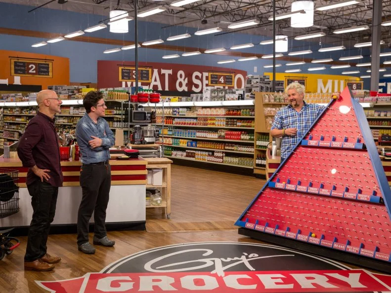 Host Guy Fieri introduces Game 3, Food Pyramid, to Celebrity Chefs Ron Ben-Israel and Justin Warner, as seen on Food Network's Guy's Grocery Games, Season 7.