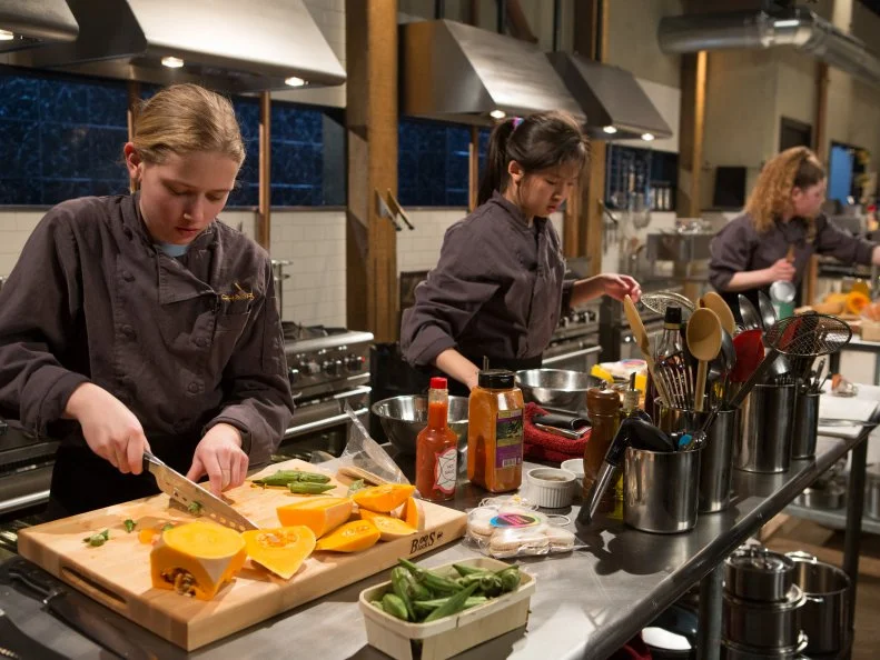 13 year old Eliza McKelvey, 13 year old Allison Lee and 14 year old Alexina Chasin work on their entree's that must include:  venison roast, butternut squash, fruity cereal macaroons and okra for Chopped Teen Week $25,000 tournament, as seen on Food Network's Chopped, Season 25.