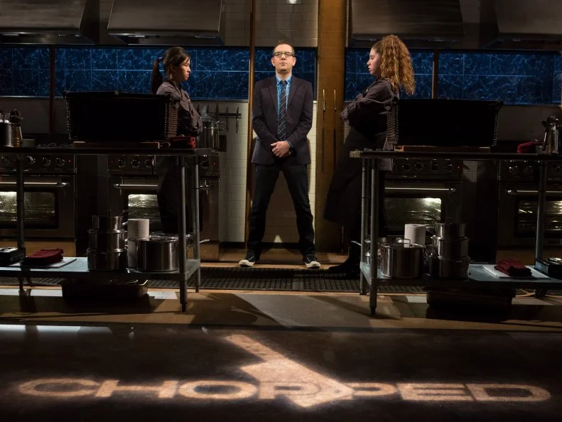 13 year old Allison Lee and 14 year old Alexina Chasin stand before Chopped host Ted Allen moments before they begin to cook in the final dessert round for Chopped Teen Week $25,000 tournament, as seen on Food Network's Chopped, Season 25.
