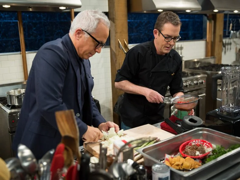 Geoffrey Zakarian and Ted Allen, during a carnival theme webisode cooking with hot beef sundae,deep fried ravioli, asparagus, and deep fried canned ham, as seen on Food Networkâ  s Chopped, season 24.