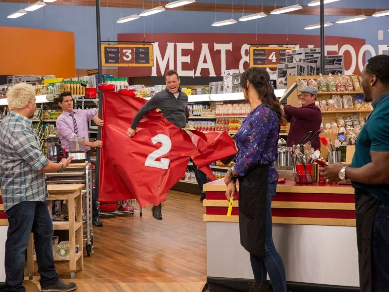 Judges Troy Johnson and Beau MacMillan reveal Celebrity Chef Brian Malarkey, as seen on Food Network's Guy's Grocery Games, Season 7.