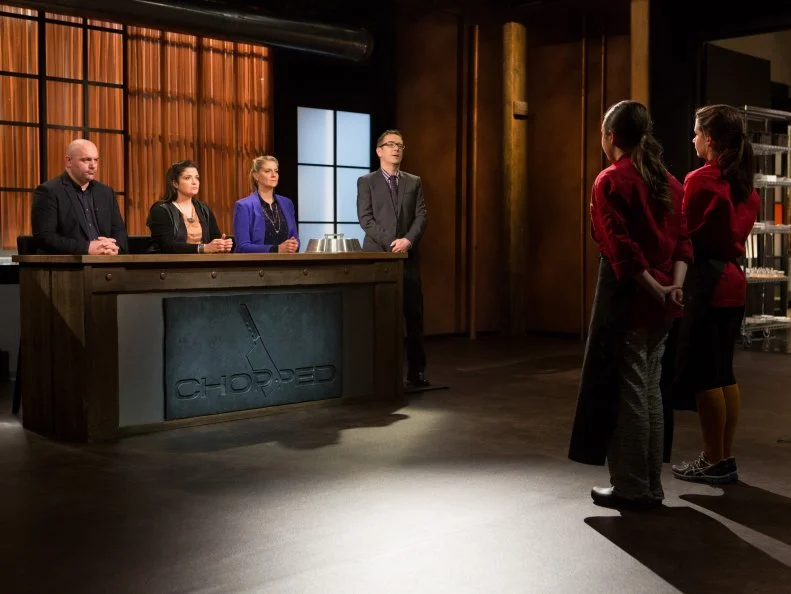 Teen Chopped champions 15 year old Veronica Seguin and 16 year old Yazmene Kaylani stand before Chopped host Ted Allen and judges: Chris Santos, Alex Guarnaschelli and Amanda Freitag moments before finding out which teen has been Chopped and which teen has won $25,0000 and the title of Chopped Grand Champion for Chopped Teen Week $25,000 tournament, as seen on Food Network's Chopped, Season 25.
