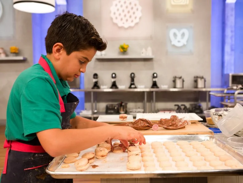 Contestant Matthew Merril begins stacking his macarons during the "Stackarons" challenge, as seen on Food Network's Kids Baking Championship, Season 2.
