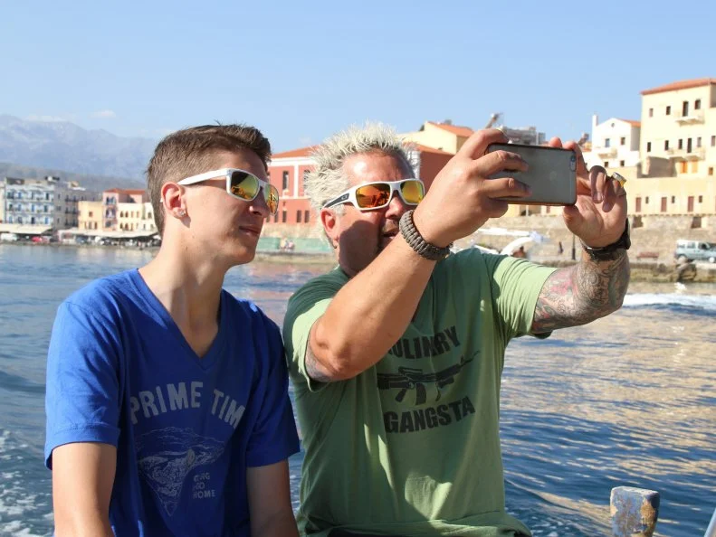 Guy and Hunter Fieri on a boat in Crete, Greece taking a selfie as seen in Food Network's Guy's European Vacation episode 1.
