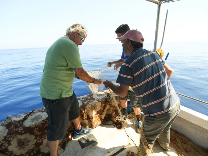 Guy Fieri, Hunter Fieri in Crete, Greece out in a boat in the Mediterranean sea helping the lobster fisherman with the lobster net as seen in Food Network's Guy's European Vacation episode 1.