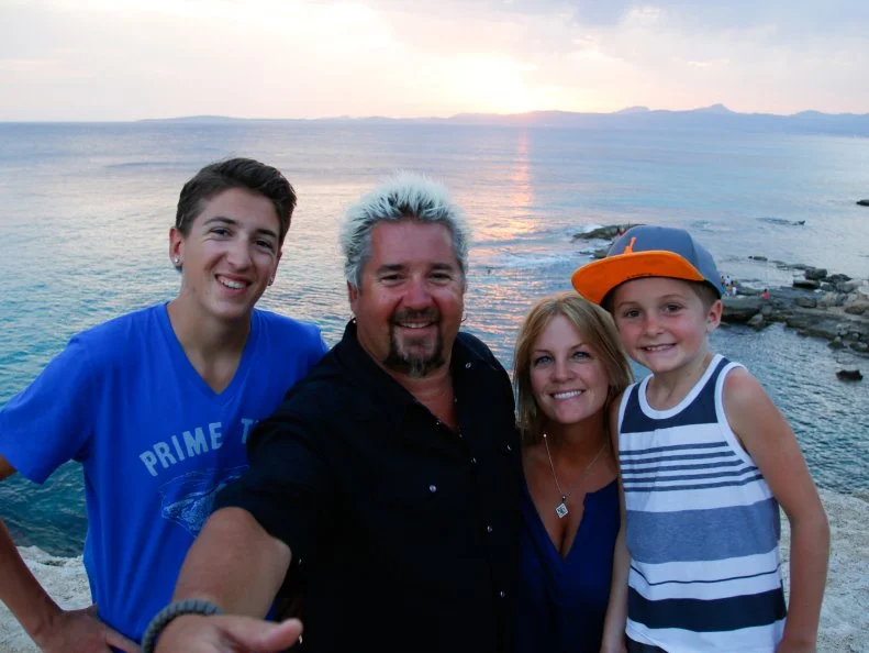 Portrait shot of the Fieri family by the ocean with the sunset in Mallorca, Spain as seen on Food Network's Guy's European Vacation episode 4.