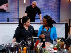 Mentors Alex Guarnaschelli and Robert Irvine observe as Lisa Washington cooks during the first challenge as seen on Food Network's All-Star Academy, Season 2.