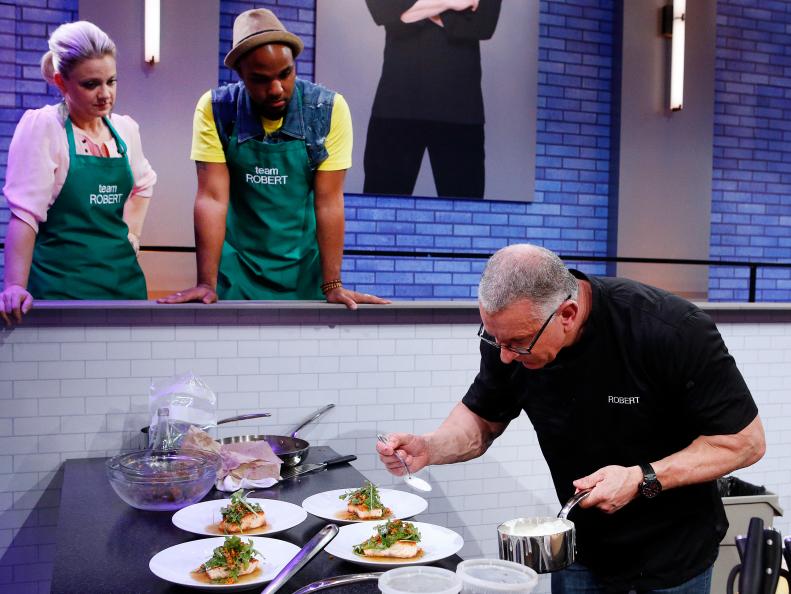 Natasha Clement and Jermaine Wright watch as their mentor Robert Irvine cooks during the second challenge as seen on Food Network's All-Star Academy, Season 2.