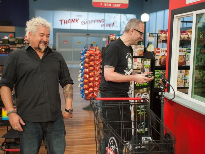 Host Guy Fieri laughs as contestant Eric Williams places his order during the "Ultimate Drive-In Burger" game, as seen on Food Network's Guy's Grocery Games, Season 8.