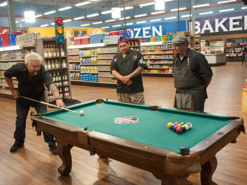 Host Guy Fieri, with contestants, Reno Henriques and Carl Ruiz explains the "Kitchen Pool" game, as seen on Food Network's Guy's Grocery Games, Season 8.