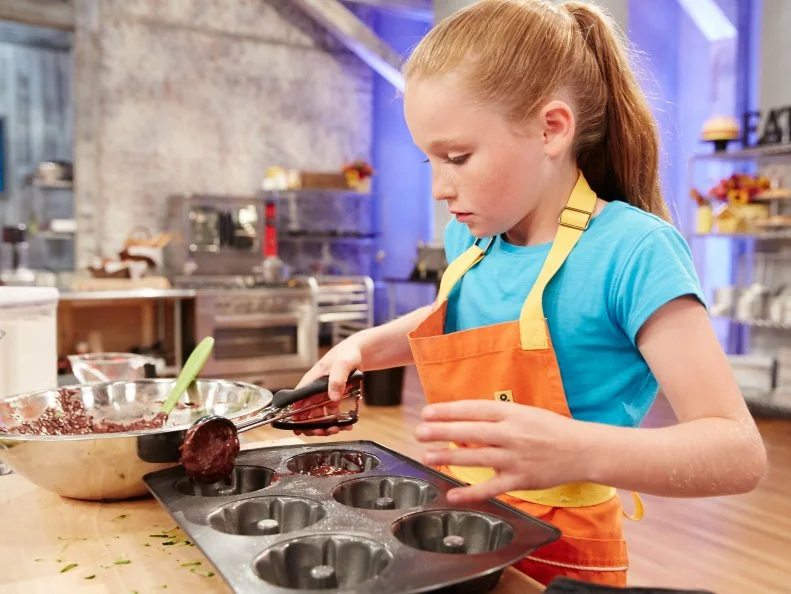 Contestant Peggy Fischer preparing her dish, Chocolate Zuchinni Cake with Tart Orange Sauce and Coconut Carrot Ice Cream, for the challenge, Lunchbox Desserts, as seen on Food Network’s Kids Baking Championship, Season 2.