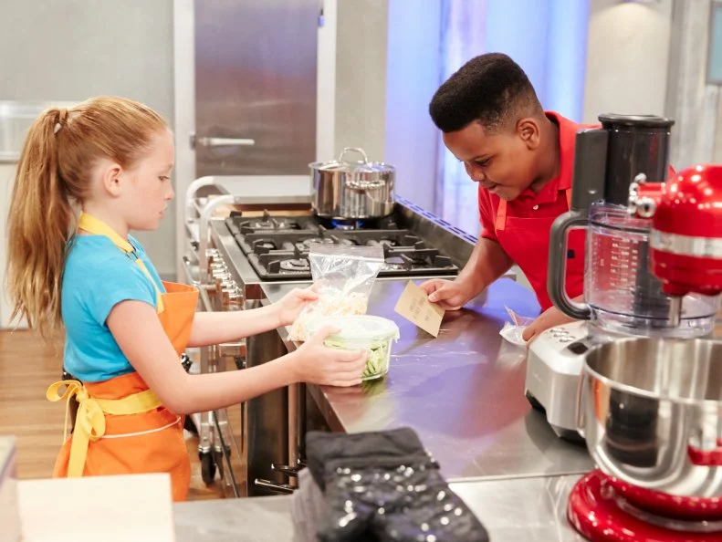 Contestants Peggy Fischer and Alex Portis, preparing their dishes for the challenge, Lunchbox Desserts, as seen on Food Network’s Kids Baking Championship, Season 2.