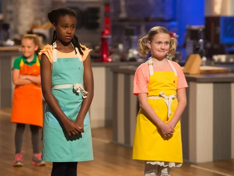 Contestants Yashimabet Sellassie and Jane Haviland await elimination after the "Candymonium" challenge, as seen on Food Network's Kids Baking Championship, Season 2.