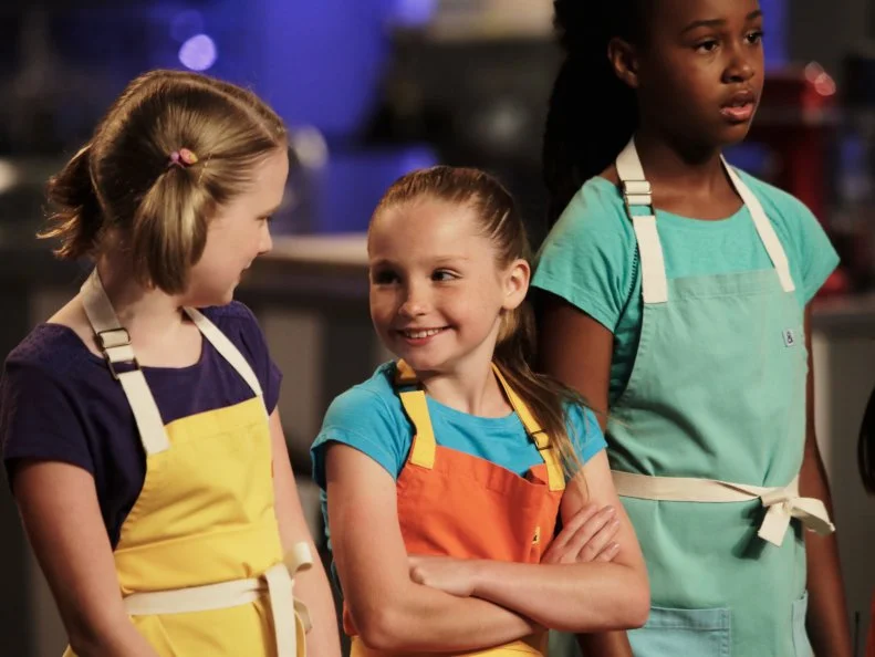 Contestants react when hearing about the "Hot Chocolate" challenge, as seen on Food Network's Kids Baking Championship, Season 2.
