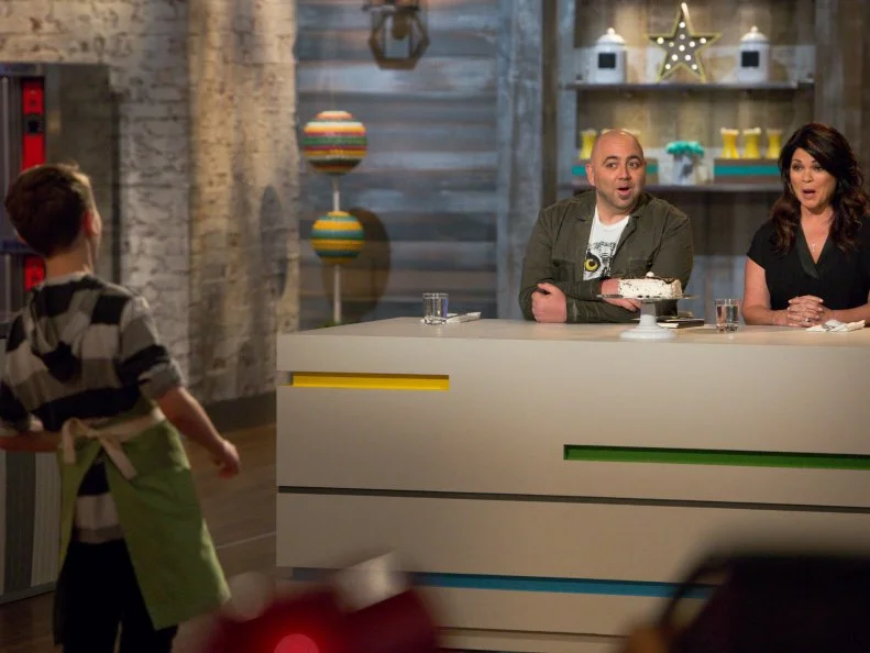 Hosts Duff Goldman and Valerie Bertinelli give contestant Colby Lacasse feedback during the "Hot Chocolate" challenge, as seen on Food Network's Kids Baking Championship, Season 2.