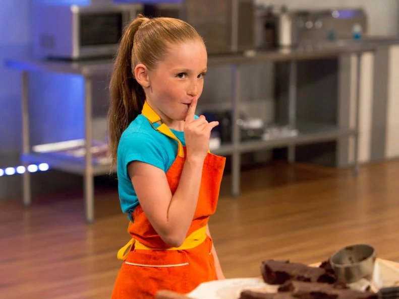 Contestant Peggy Fischer sneaks a bite of chocolate during the "Hot Chocolate" challenge, as seen on Food Network's Kids Baking Championship, Season 2.