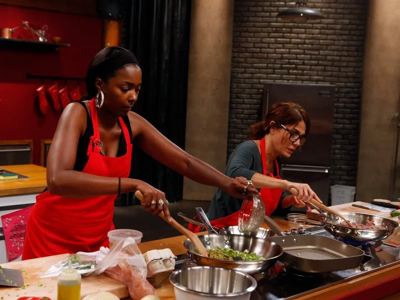 Red team recruits Chanda Havard, left, and Glenda Galeano prepare their empanada elimination challenge dishes as seen on Food Network's Worst Cooks in America, Season 8.