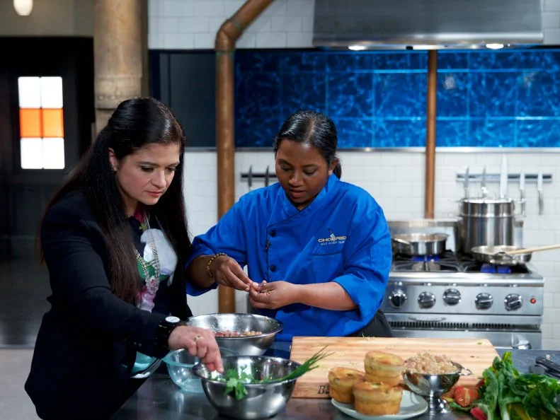 Judge Alex Guarnaschelli (L) with chef Aarthi Sampath as she cooks Goat and currant kofta with Swiss chard "saag" and chard stem and egg muffin crumble, during the entrŽe round, as seen on Food Network's Chopped, Season 31.