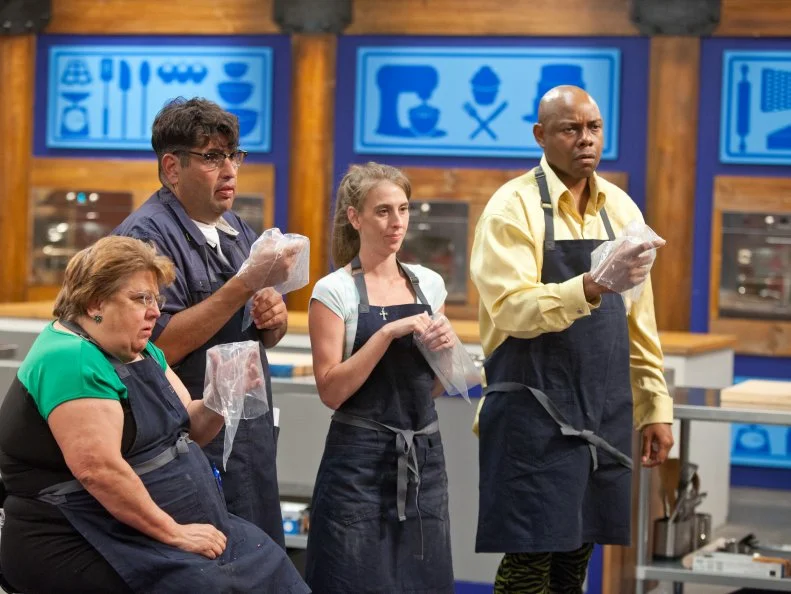 The BlueTeam listens and watches Host Duff Goldman do a kitchen demo as he teaches his team how to make mini vanilla wedding cupcakes for their next competition, as seen on Food Network's Worst Bakers In America, Season 1.