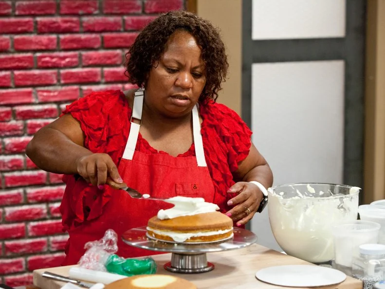 Contestant Carla Johnson spreads her butter cream icing over her birthday cake, as seen on Food Network's Worst Bakers In America, Season 1.
