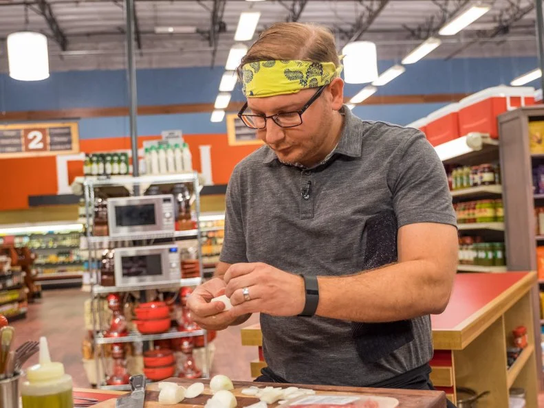Contestant Brian Goodman peels onions, as seen on Food Network's Guy's Grocery Games, Season 11.