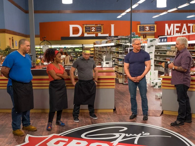 Host Guy Fieri speaks with contestants Kevin Champion, Toya Boudy, Brian Goodman and judge Robert Irvine, as seen on Food Network's Guy's Grocery Games, Season 11.