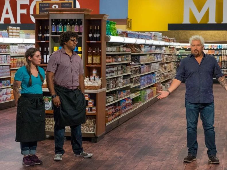 Host Guy Fieri speaks to contestants Samantha Mitchel and Stephen Jones, as seen on Food Network's Guy's Grocery Games, Season 11.