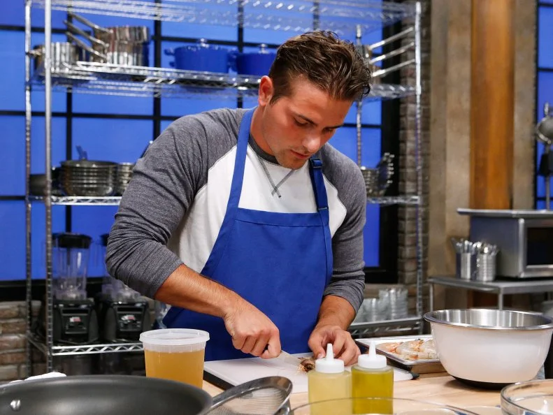 Jake Michaels of the blue team cooks during the main dish challenge, as seen on Food Network's Worst Cooks in America, Season 10.