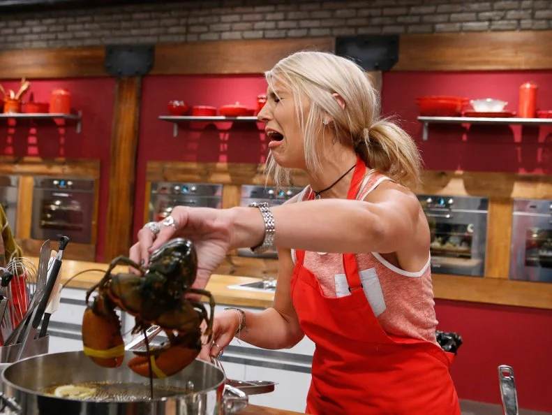 Mandy Thornton of the red team reacts to handling a live lobster as she cooks during the main dish challenge, as seen on Food Network's Worst Cooks in America, Season 10.