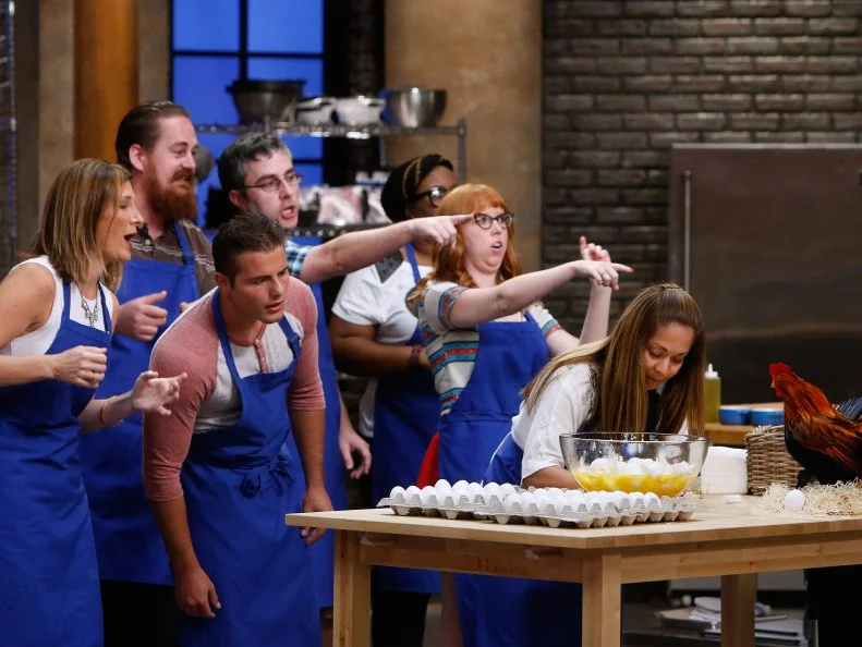 Maria Marcello cracks eggs as her blue teammates look on during a game of Egg-Zact Match, as seen on Food Network's Worst Cooks in America, Season 10.