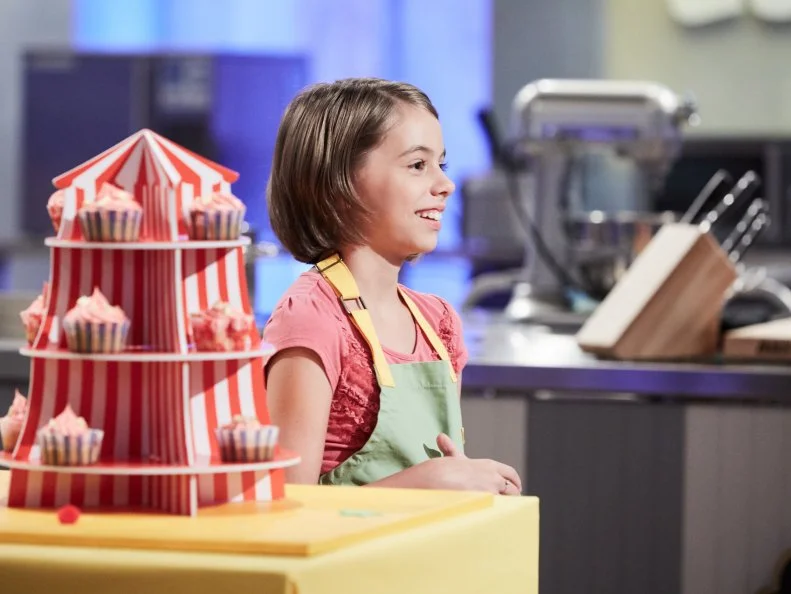 Contestant Audra Tow presenting her Main Heat dish, Lemon Cupcake with Caramel Icing and Apple Sprinkles, with the Caramel Apple Carnival Treat, as seen on Food Network's Kids Baking Championship, Season 3.