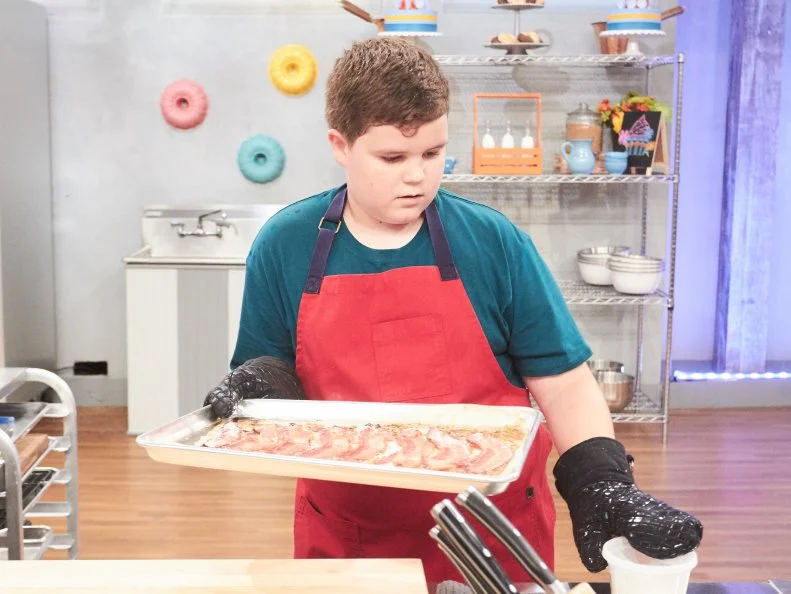 Contestant Aidan Berry preparing his Main Heat dish, Maple Cupcake with Maple, Chocolate Banana Frosting and Bacon, with the Chocolate Covered Banana Carnival Treat, as seen on Food Network's Kids Baking Championship, Season 3.