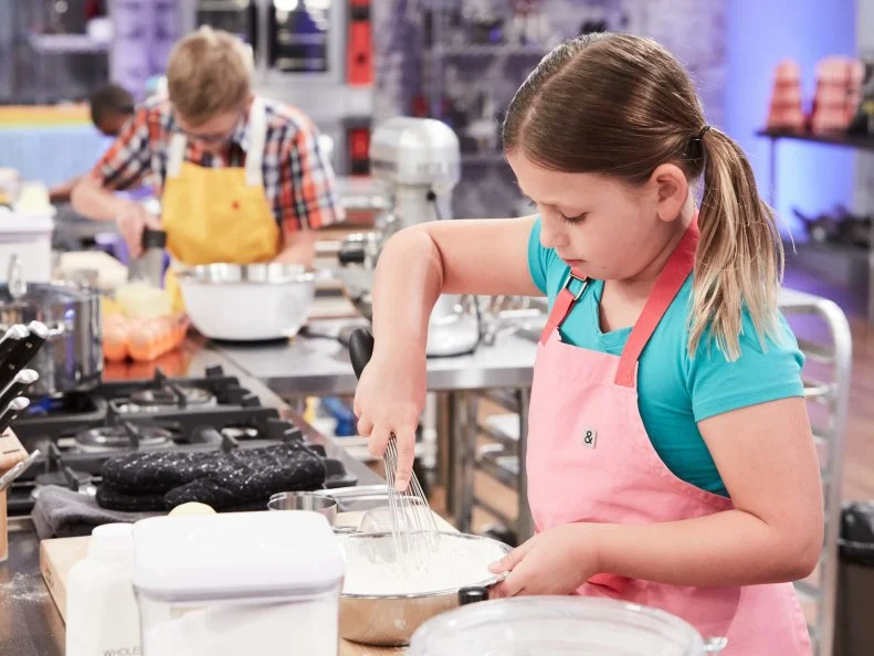Contestant Brooke Cumberland preparing her Main Heat dish, Lemon Cupcake with Vanilla Buttercream and Sweet Pretzel Filling, with the Pretzel Carnival Treat, as seen on Food Network's Kids Baking Championship, Season 3.
