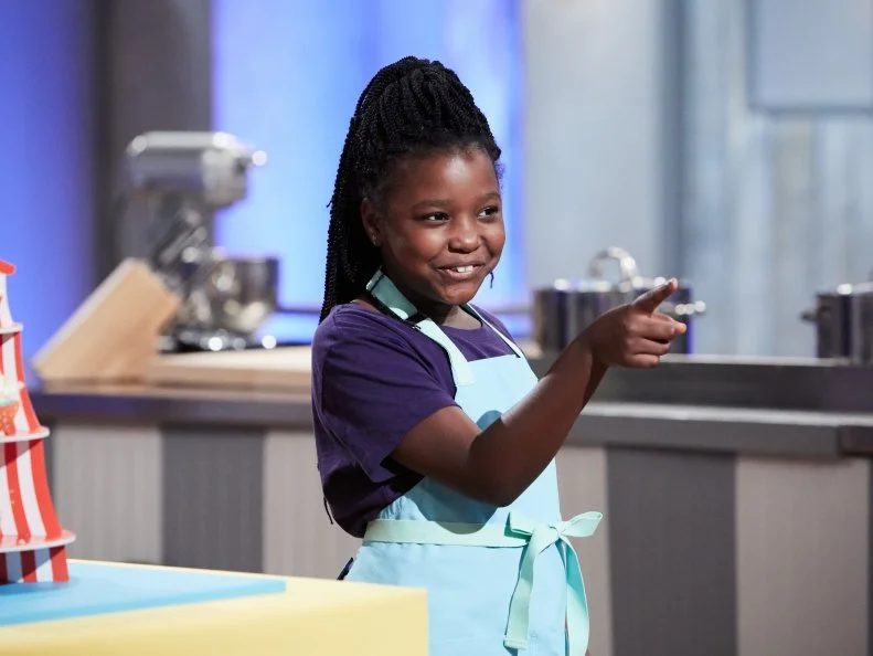 Contestant Kaniyah Cary presenting her Main Heat dish, Vanilla Kettle Corn Cupcake with Vanilla Buttercream, with the Kettle Corn Carnival Treat, as seen on Food Network's Kids Baking Championship, Season 3.