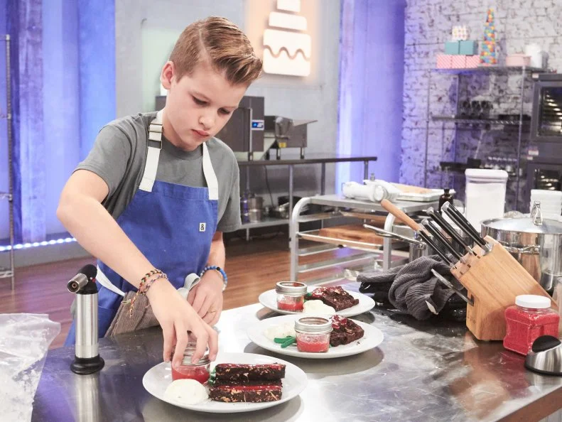 Contestant Cole Frederickson preparing his Main Heat dish, Meatloaf with Coffee Chocolate Cake "Meatloaf", Strawberry Coulis "Ketchup", Hazelnut Banana Buttercream "Mashed Potatoes", and Green Modeling Chocolate "Green Beans", as seen on Food Network's Kids Baking Championship, Season 3.