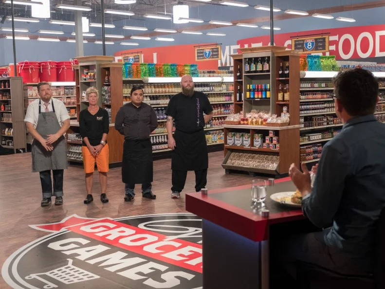 Contestants Peter Campbell, Brigitte Blodsoe, Lou Ramirez and Louie Finnan listen as the judges critique their dishes, as seen on Food Network's Guy's Grocery Games, Season 12.