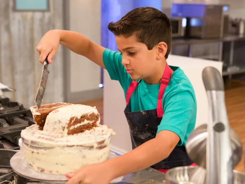 Contestant shapes his amusement park themed chocolate cake for the final challenge, "Spring Break Cakes", as seen on Food Network's Kids Baking Championship, Season 2.