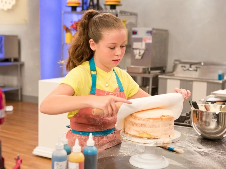 Contestant Rebecca Beale rolls fondit onto her beach themed Lemon Cake for the final challenge, "Spring Break Cakes", as seen on Food Network's Kids Baking Championship, Season 2.
