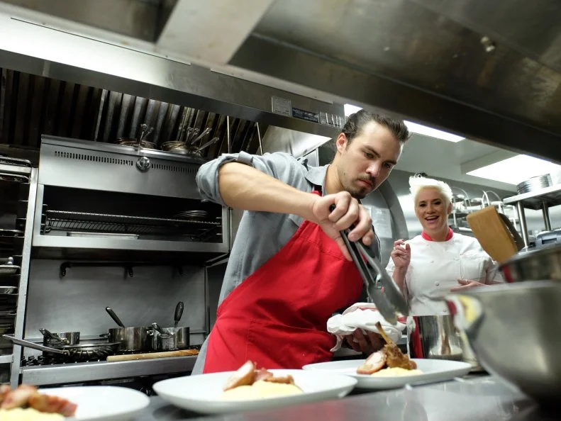 Host, Anne Burrell works with finalist, Nick Slater on a menu of goat cheese stuffed fried zucchini blossoms with zucchini noodles; stuffed rabbit loin with chanterelles, fava beans and soft polenta;  cherry crostata with vanilla ice cream, as seen on Food Network’s Worst Cooks In America, Season 8.
