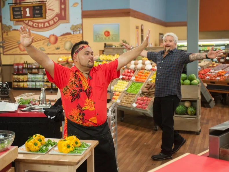 Contestant Kaimana Chee raises his hands as time is up, as seen on Food Network's Guy's Grocery Games, Season 9.