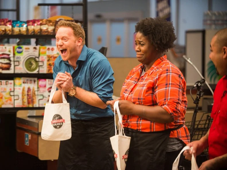 Contestants Bourke Floyd, Reva Constantine and Chris Tzorin hold small bags for the "Think Small" competition, as seen on Food Network's Guy's Grocery Games, Season 9.