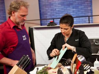 Mentor Alex Guarnaschelli teaches cook Lee Abbot the proper way to use a mandoline, as seen on Food Network's All-Star Academy, Season 2.