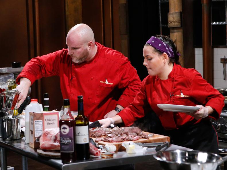 Chefs Adam Greenberg and Deborah Caplan cook with leg of lamb, blue cheese lollipops, cognac and cardones during the entree round, as seen on Food Network's Chopped, Season 28.