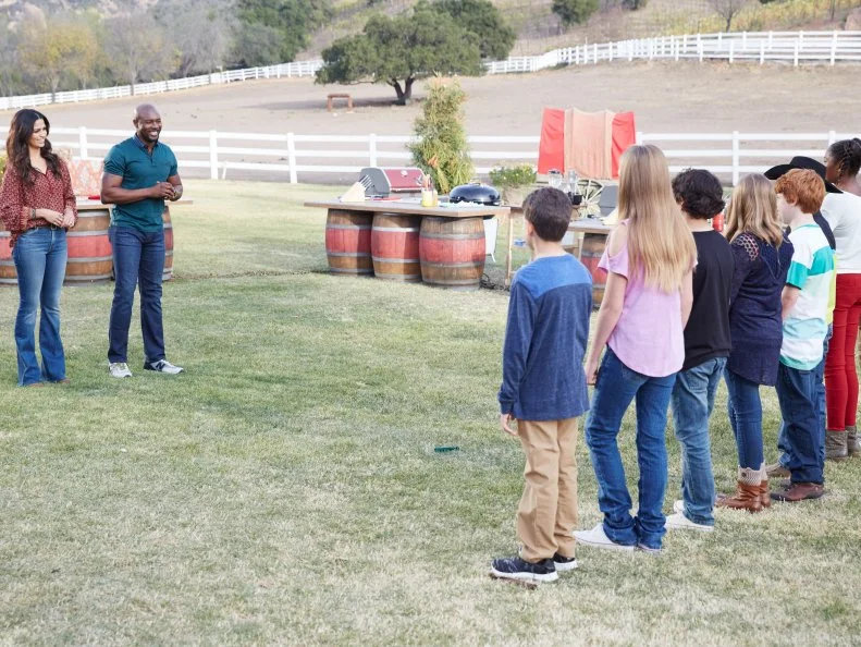 Hosts Camila Alves and Eddie Jackson, and contestants Tyler Zager, Carter Hull, Paris Hale, Ty Machado, Josie Burkhardt, Sydney Groves, Jacob Scott, and LJ Ruth, during the Chicken BBQ Challenge, as seen on Food Network’s Kids BBQ Challenge Season 1.