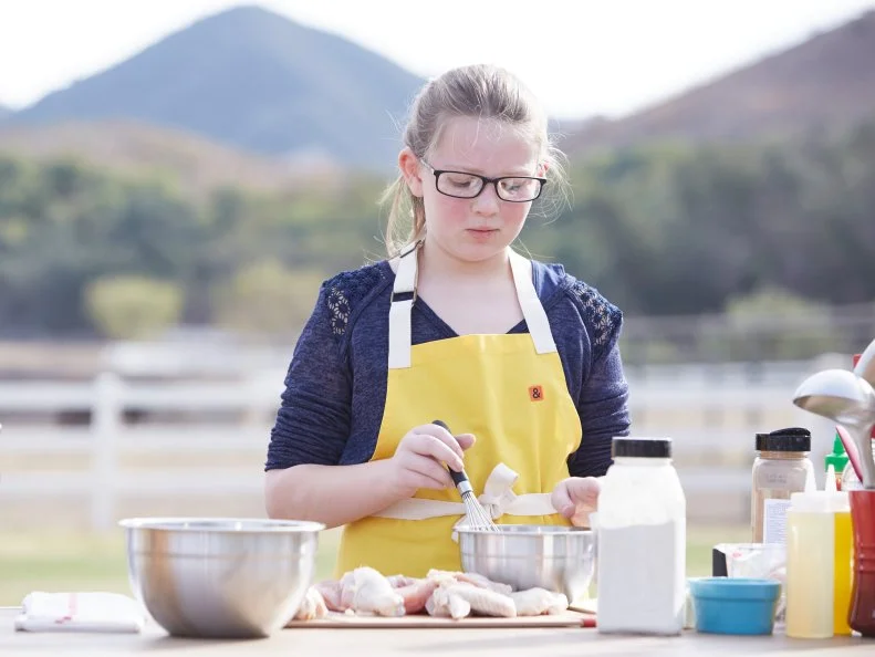Contestant Sydney Groves prepares her dish for the Chicken BBQ Challenge, as seen on Food Network’s Kids BBQ Challenge Season 1.