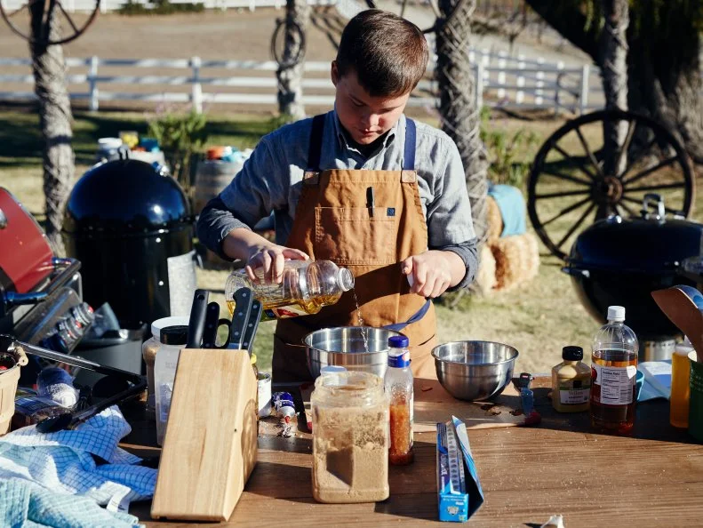 Contestant Carter Hull preparing his dish for the Pit Master BBQ Challenge, as seen on Food Network’s Kids BBQ Challenge Season 1.