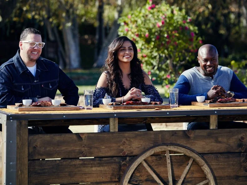 Guest Judge Graham Elliot and Hosts Camila Alves and Eddie Jackson sample the contestants' dishes during the Pit Master BBQ Challenge, as seen on Food Network’s Kids BBQ Challenge Season 1.