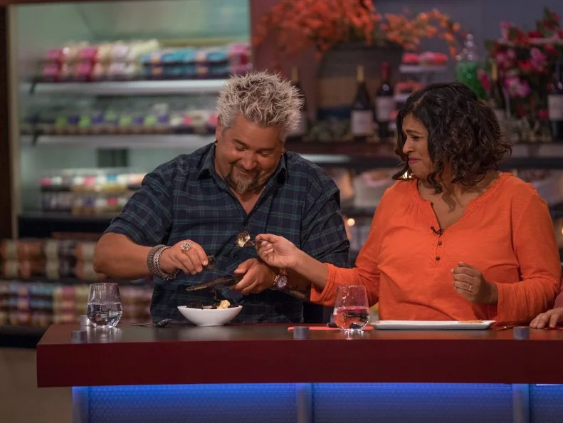 With the assistance of judge Aarti Sequeira, host Guy Fieri tries contestant Damaris Philips's Truffle Mac and Cheese with Peanut Butter Grape Coutuie, as seen on Food Network's Guy's Grocery Games, Season 10.