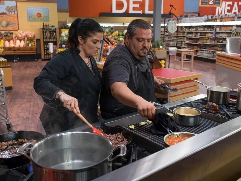 Contestant Eric Greenspan works on the sauce while Alex Guarnaschelli stirs the beef, as seen on Food Network's Guy's Grocery Games, Season 10.